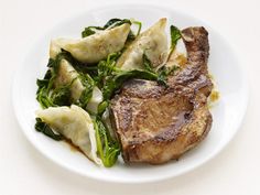 a white plate topped with meat and veggies on top of a white table