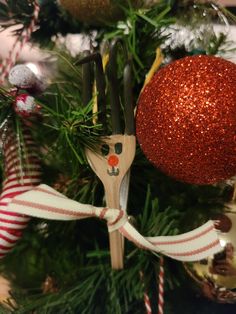 a christmas ornament with scissors and ribbon hanging from it's side on a tree