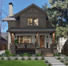 a house that is in the middle of some grass and plants on the front lawn