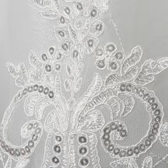 closeup of white lace with beads and flowers on the bottom part of a veil