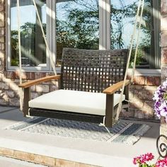 a chair that is sitting in front of a window with flowers on the ground next to it