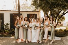 a group of women standing next to each other in front of a house with flowers