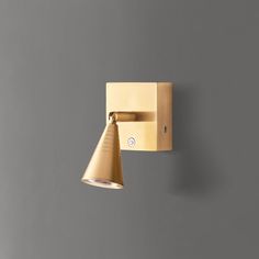 a wall mounted light on the side of a gray wall next to a wooden block