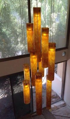 a chandelier made out of glass bottles in front of a window with trees outside