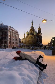 a person laying in the snow next to a building with domes on it's sides