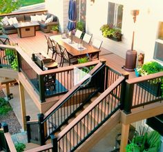 an outdoor deck with patio furniture and umbrellas on the top floor, surrounded by greenery