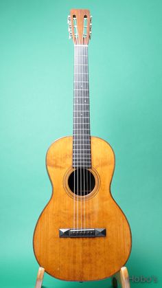 an ukulele sits on a stand against a green background