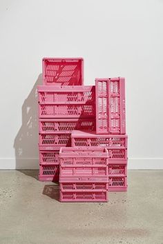 pink crates stacked on top of each other in front of a white wall and floor