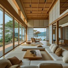 a living room with couches, tables and large windows overlooking the water's edge