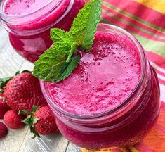 two mason jars filled with smoothie next to strawberries