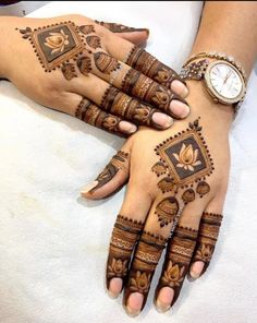 two hands with henna tattoos on them, one is wearing a watch and the other has