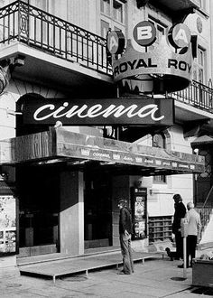 black and white photograph of people walking in front of a royal hotel