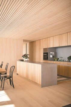 a kitchen and dining room with wood flooring is shown in this image, there are many chairs around the table