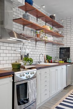 a kitchen with white cabinets and open shelving above the stove, has a black and white striped rug on the floor