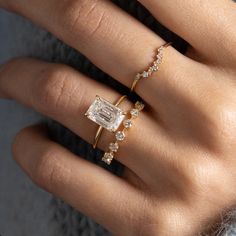 a woman's hand with two rings and an engagement ring on top of her finger