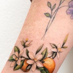 an orange and flowers tattoo on the arm