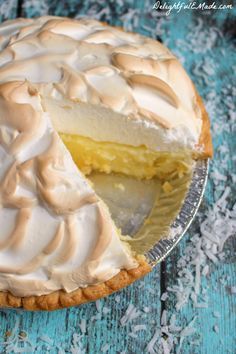 a pie with white frosting sitting on top of a blue wooden table next to a knife