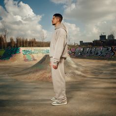 a man standing in front of a skateboard ramp with graffiti on the walls behind him