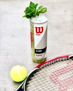 a drink and tennis racket sitting on the ground