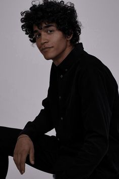 a young man with curly hair sitting down