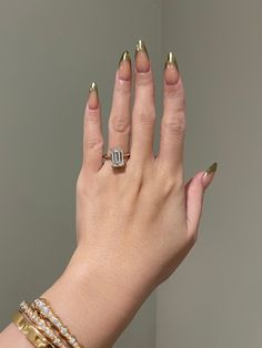 a woman's hand with gold nail polish and two rings on her left wrist