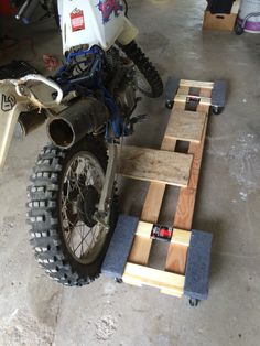 a dirt bike is being worked on in a garage with wooden boards attached to it