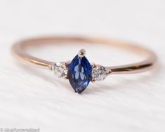 a gold ring with two pear shaped blue sapphires and three white diamonds on it