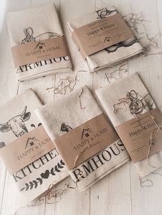 six tea towels are laid out on a white wood floor with tags attached to them