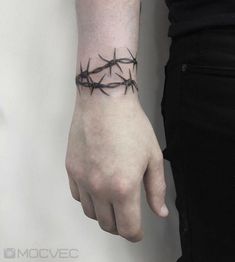 a person wearing a wrist tattoo with barbed wire on it