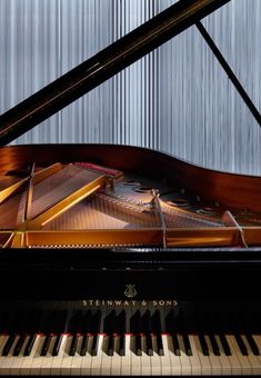 a grand piano sitting in front of a metal wall