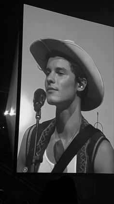 a black and white photo of a man wearing a cowboy hat with a microphone in front of him