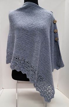 a woman's shawl with buttons on the front and back, sitting on top of a mannequin