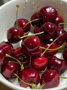 a white bowl filled with cherries on top of a table