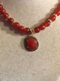 This necklace is made of a carnelian pendant surrounded by white topaz stones, 8mm carnelian gemstones, gold filled: beads, spring ring clasp and findings. This necklace measures 18 inches in length and the pendant is about 3/4 inch. All of our jewelry is unique and custom designed. Most of our jewelry can easily be resized. If there is a piece of jewelry that you are interested in, but would like some changes made, please do not hesitate to contact us. We appreciate your shopping with Jewelry b Luxury Single Strand Carnelian Jewelry, Luxury Carnelian Faceted Beads Necklace, Elegant Carnelian Beaded Necklace With Natural Stones, Elegant Carnelian Gemstone Bead Jewelry, Elegant Beaded Necklace With Carnelian Stones, Elegant Red Gemstone Beads And Cabochons, Carnelian Beaded Necklaces With Round Stones, Carnelian Beaded Necklaces With Stones, Elegant Carnelian Beaded Necklace With Gemstone Beads