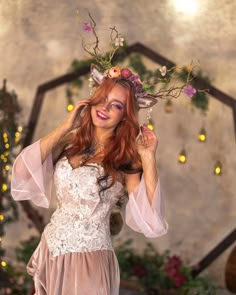 a woman with red hair wearing a white dress and flower crown standing in front of a mirror