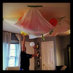 a man is playing with plastic balls in the air above his living room table and couch