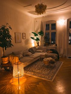 a living room filled with lots of furniture and plants on top of a hard wood floor