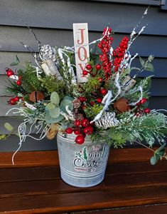 a bucket filled with red berries and greenery next to a sign that says joy