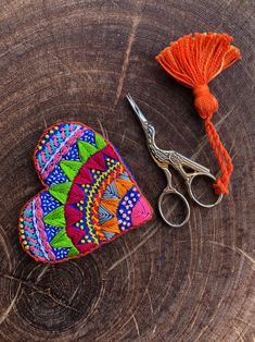 a pair of scissors sitting on top of a piece of wood next to a heart shaped purse