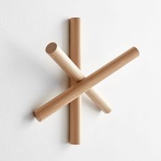 two wooden sticks sticking out of each other on top of a white surface with one stick in the middle