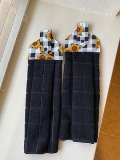 two black oven mitts with sunflowers on them sitting on a counter top