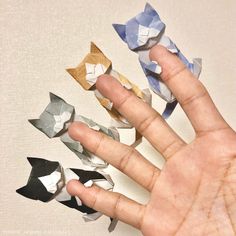 the hand is holding several small origami pieces