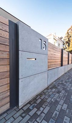 the number fifteen is on the concrete wall next to the brick sidewalk and trees in the background