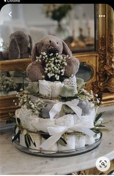 a teddy bear sitting on top of a diaper cake with baby's breath