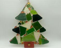 a glass christmas tree ornament with green and red tiles on it's sides