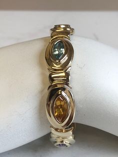 "14kt Yellow Gold Lady's Semi-Precious Multi Color Bracelet in 7\" consisting of 7- 11mm x 5mm Marquise Shape Semi-Precious Genuine Gemstones. Semi-Precious Gemstones include 3- Citrine, 2- Amethyst and 2- Blue Topaz all bezel set by our Master Goldsmith in a solid hinged 1/2\" wide bracelet with a large solid box clasp and a fig 8 safety clasp closure. Total weight of Bracelet is 33.0 grams. This item would Retail for $3,950.00" Yellow Gold Marquise Multi-stone Jewelry, Heirloom Yellow Gold Multi-stone Bracelets, Color Bracelet, Wide Bracelet, Box Clasp, Colorful Bracelets, Precious Gemstones, Gold Hoop, Mens Wedding Bands