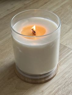 a lit candle sitting on top of a wooden table next to a glass container filled with liquid