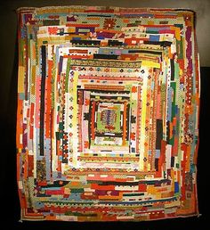 a multicolored quilt is hanging on the wall in front of a black background