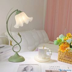 a table that has some flowers on it and a lamp in front of the table