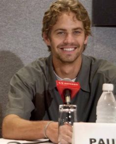 a man sitting at a table with a microphone in front of him and a sign that says paul